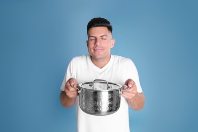 Happy man with pot on light blue background