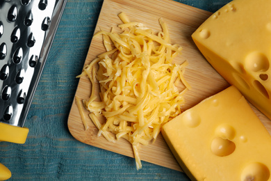 Photo of Tasty grated cheese on blue wooden table, flat lay
