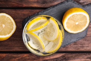 Photo of Soda water with lemon slices on wooden table, flat lay