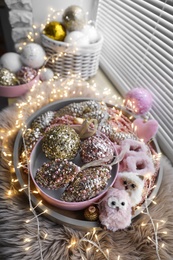 Photo of Beautiful Christmas tree baubles, toys and fairy lights on window sill indoors