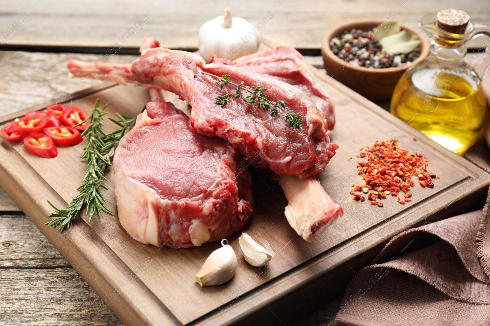 Photo of Fresh tomahawk beef cuts and spices on wooden table, closeup