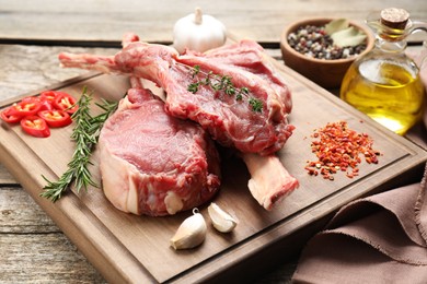 Photo of Fresh tomahawk beef cuts and spices on wooden table, closeup