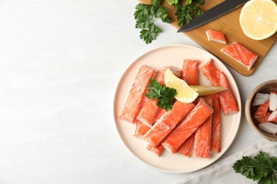 Photo of Flat lay composition with crab sticks and lemon on white table, space for text