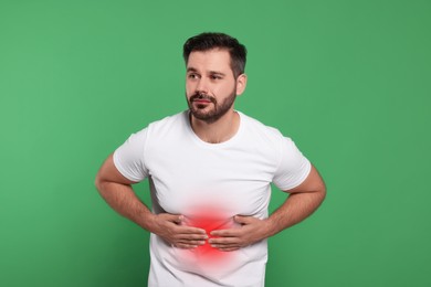 Man suffering from stomach pain on green background