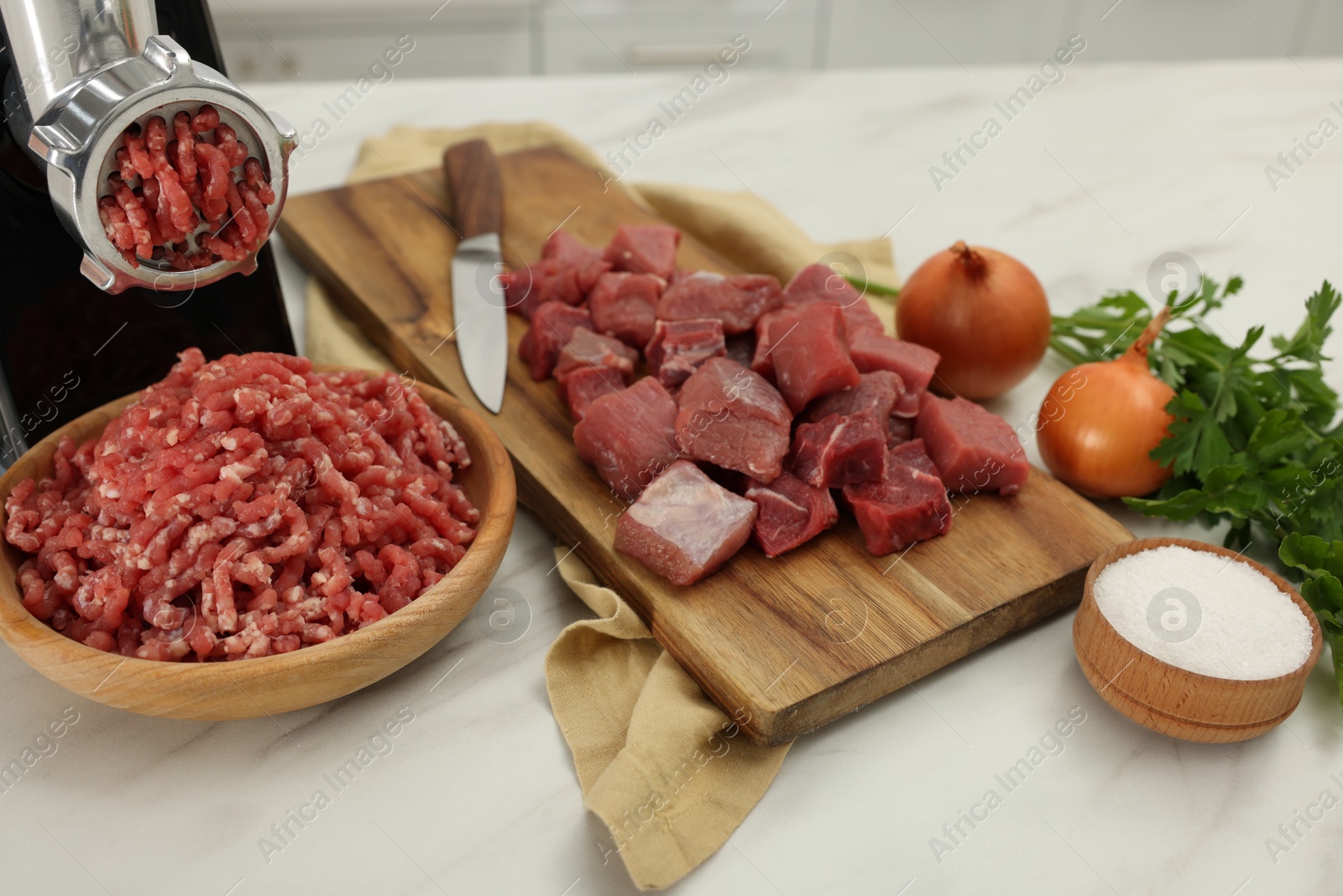 Photo of Electric meat grinder with beef and products on white marble table
