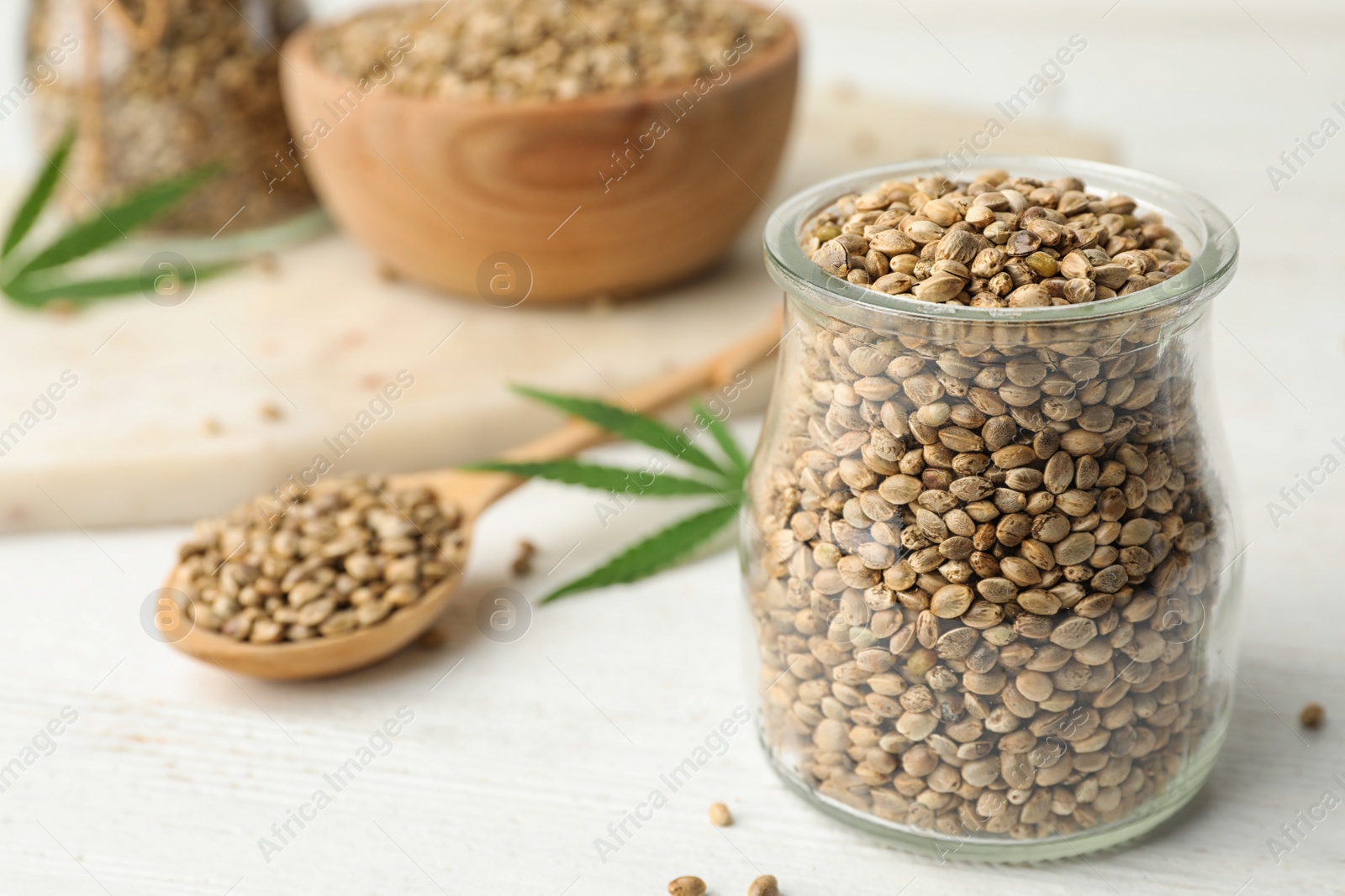 Photo of Organic hemp seeds and leaf on white table