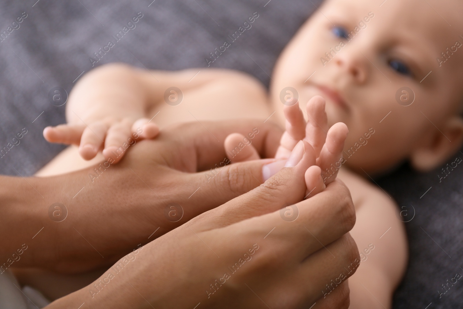 Photo of Woman massaging cute little baby on blanket, closeup