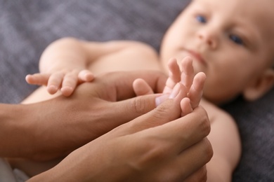 Woman massaging cute little baby on blanket, closeup