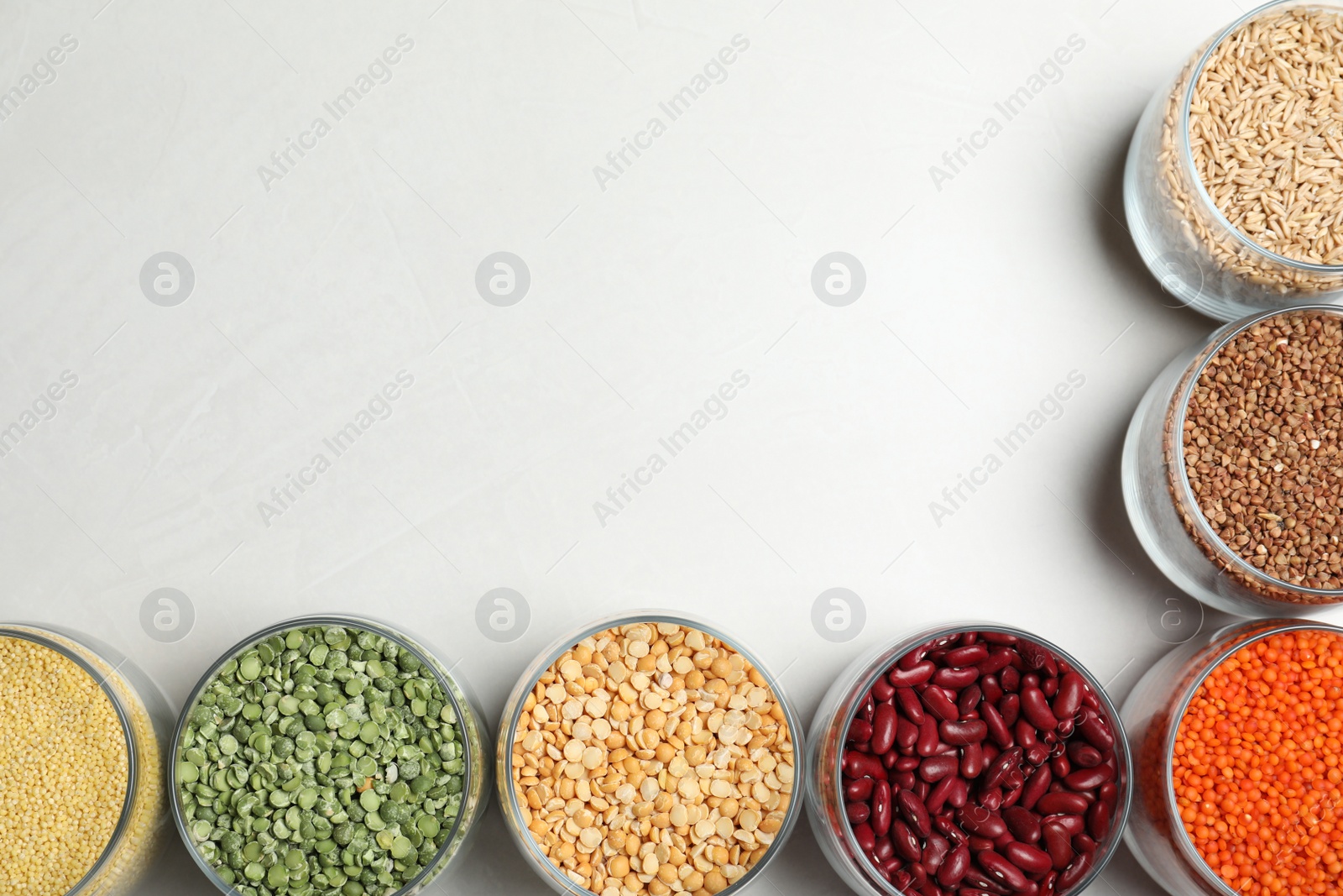 Photo of Jars with different cereals on white background, flat lay. Space for text