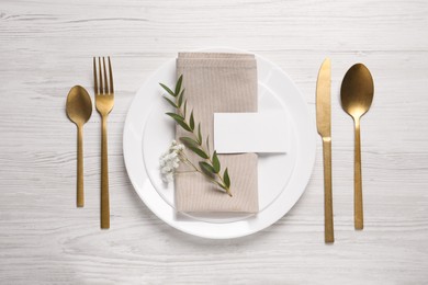 Photo of Stylish setting with cutlery, eucalyptus leaves and blank card on white wooden table, flat lay. Space for text