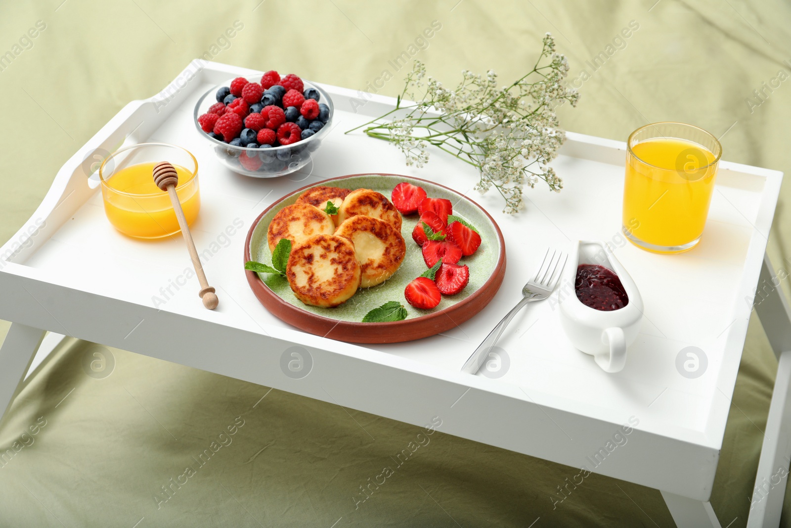 Photo of Delicious cottage cheese pancakes with fresh berries and mint served on white bed tray