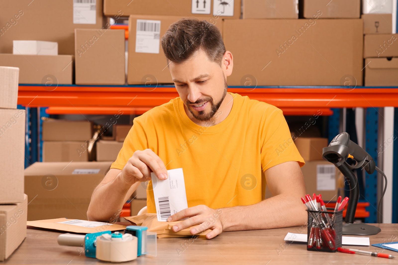 Photo of Post office worker sticking barcode on parcel at counter indoors