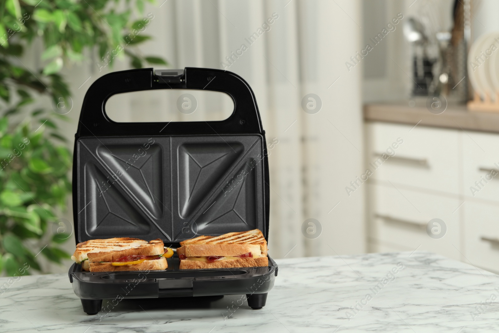 Photo of Modern grill maker with sandwiches on white marble table in kitchen, space for text