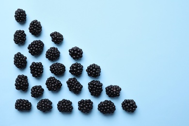Tasty ripe blackberries on light blue background, flat lay. Space for text
