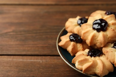 Photo of Tasty shortbread cookies with jam on wooden table, closeup. Space for text