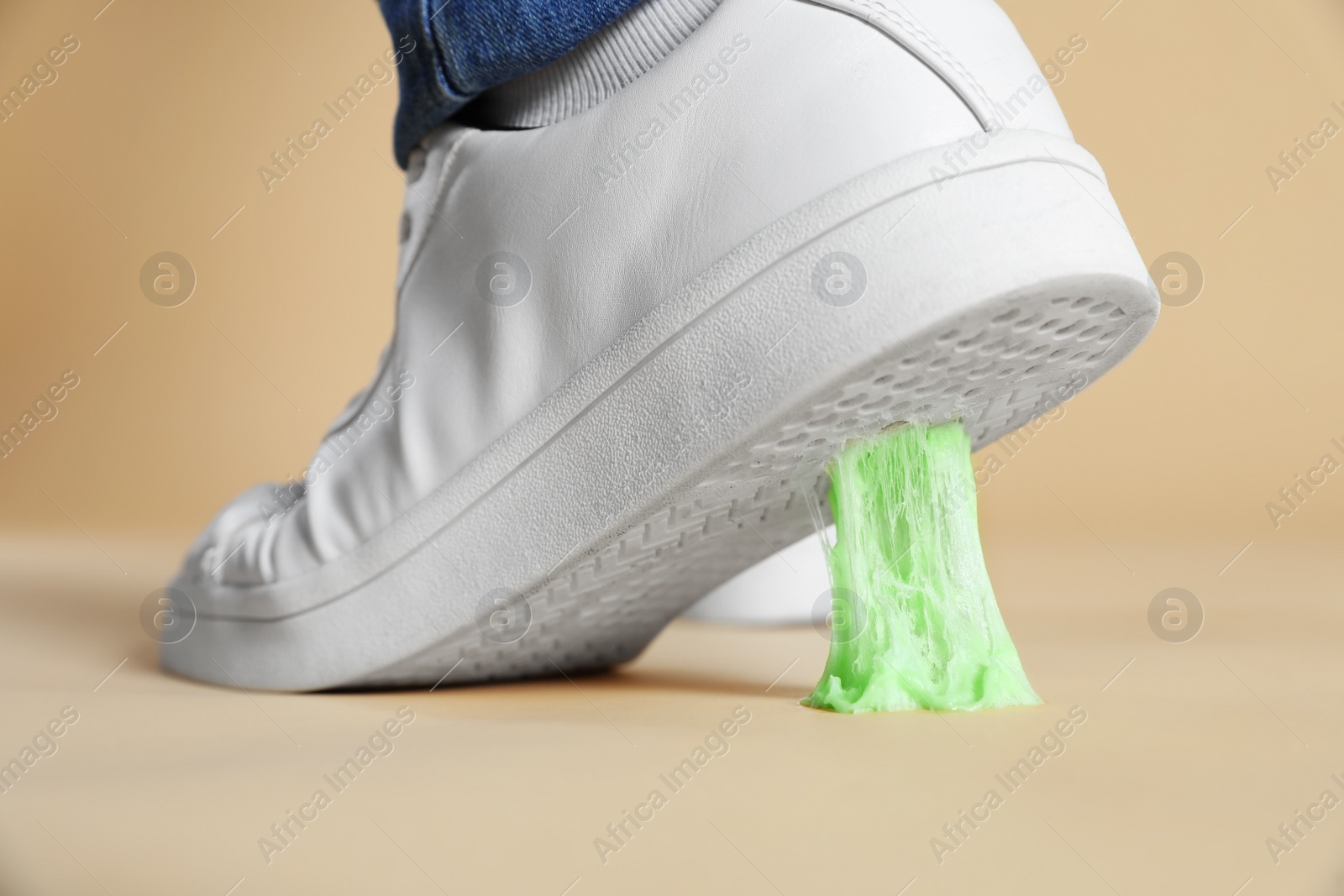 Photo of Person stepping into chewing gum on light brown background, closeup