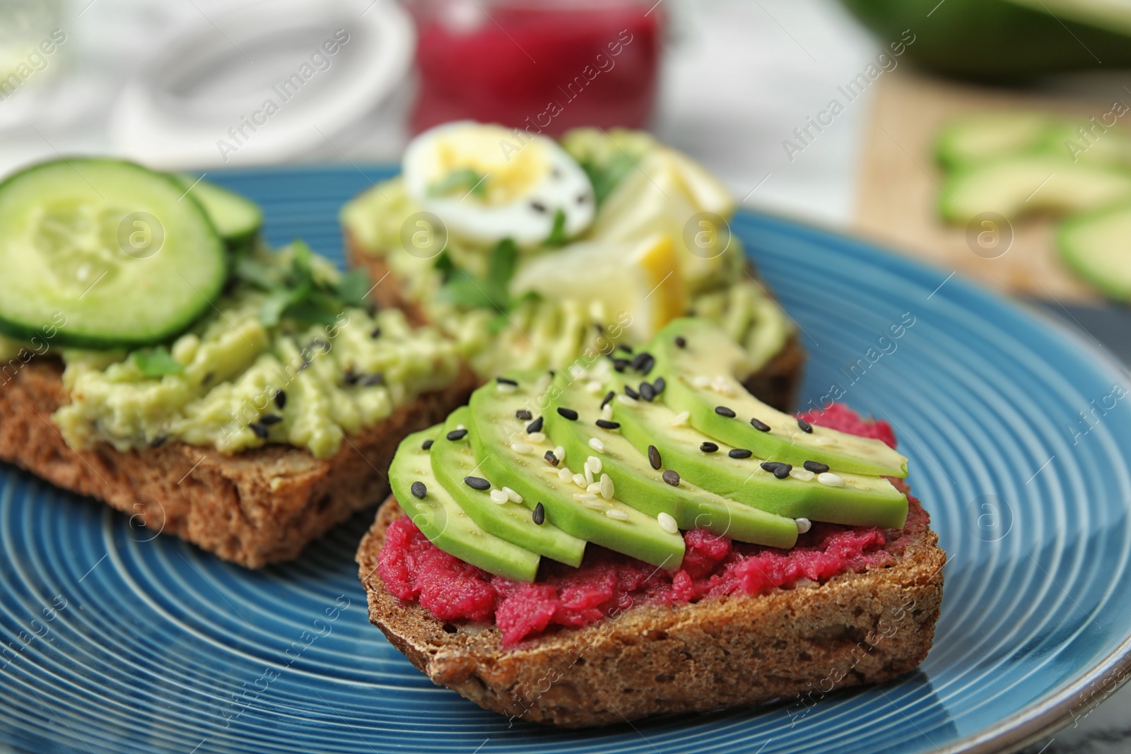 Photo of Crisp rye toasts with avocado on plate, closeup