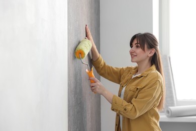 Photo of Woman hanging stylish gray wallpaper in room