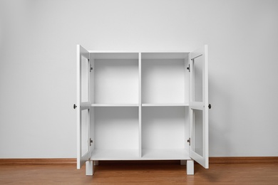 Photo of Empty wooden cabinet near white wall. Stylish home furniture