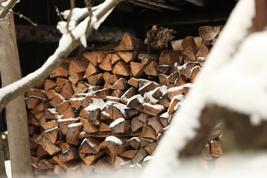 Photo of Large pile of firewood covered with snow outdoors