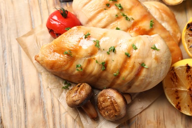 Grilled chicken breasts with garnish on wooden background, top view