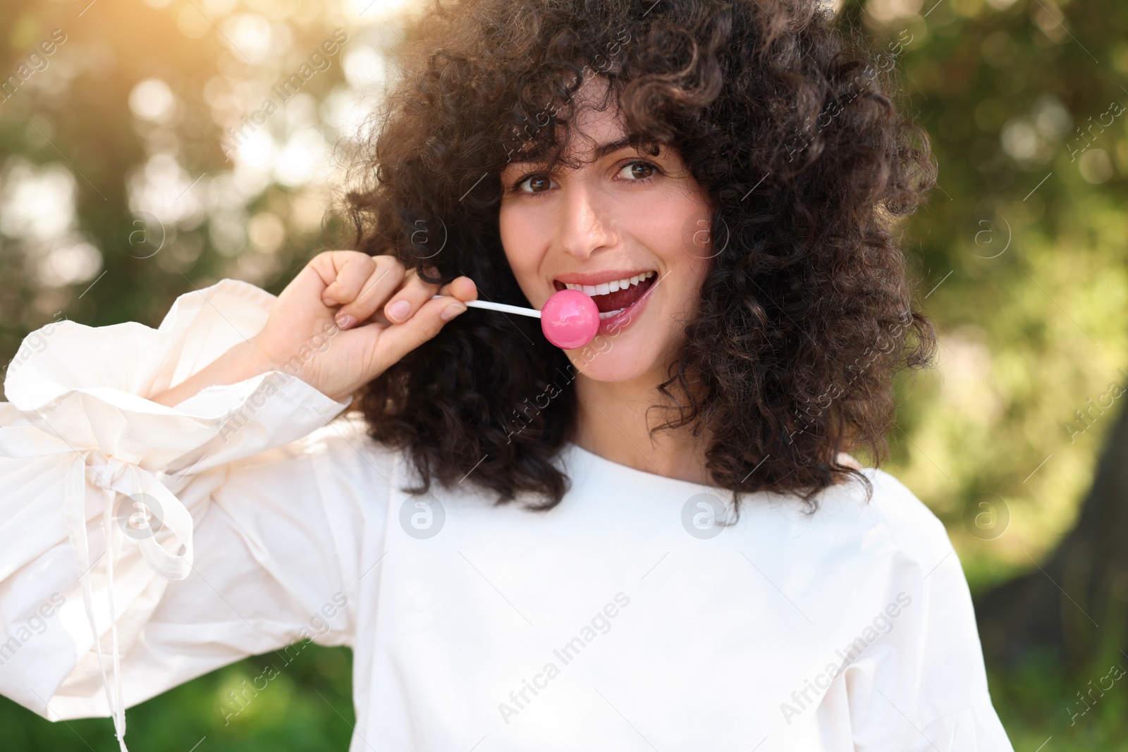 Photo of Beautiful woman in white blouse with lollipop outdoors