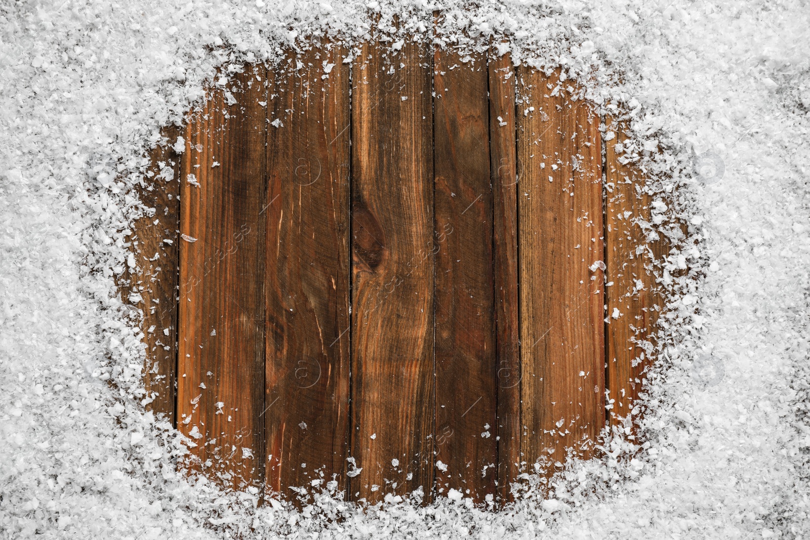 Photo of Frame of white snow on wooden background, top view with space for text. Christmas season