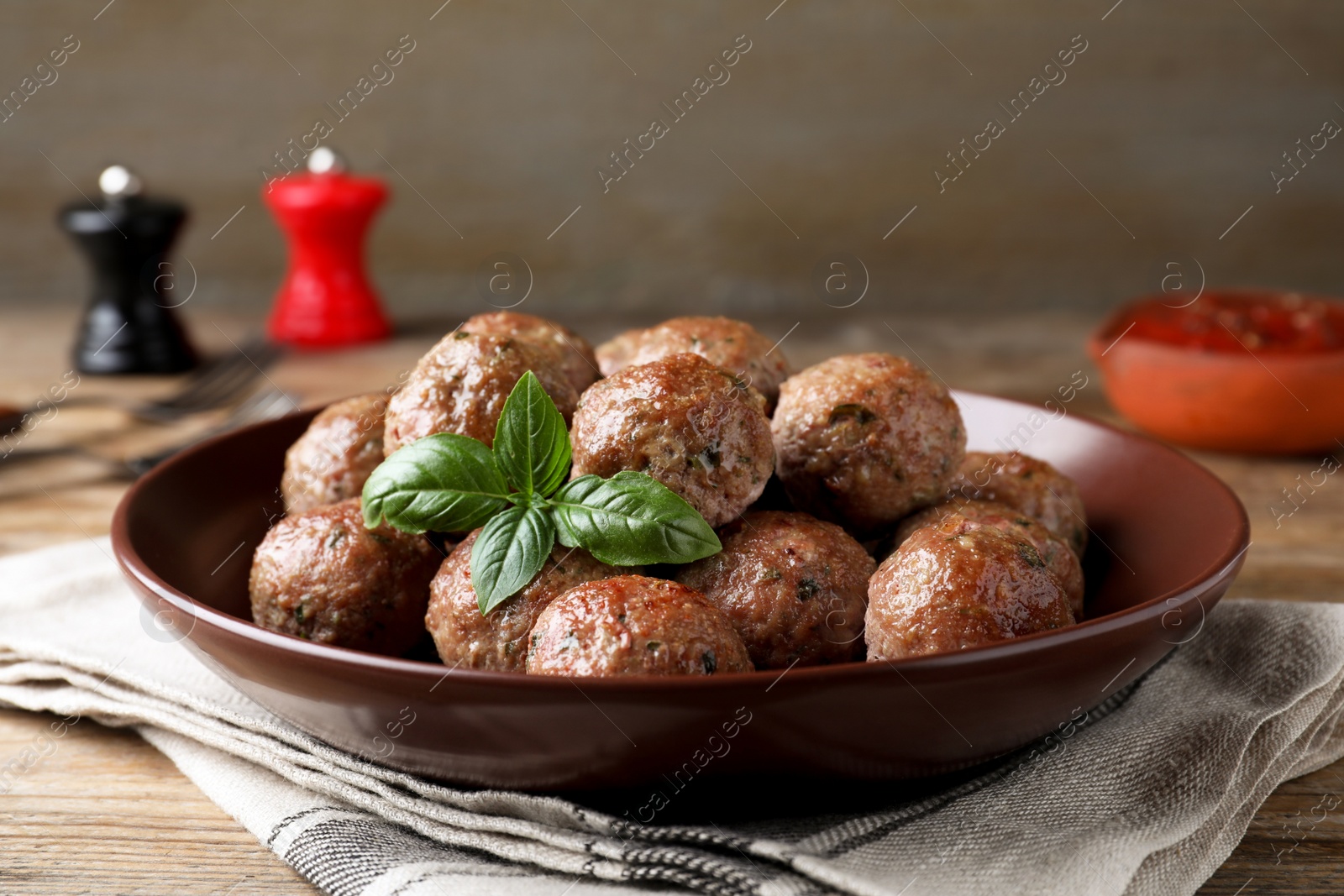 Photo of Tasty cooked meatballs with basil served on wooden table