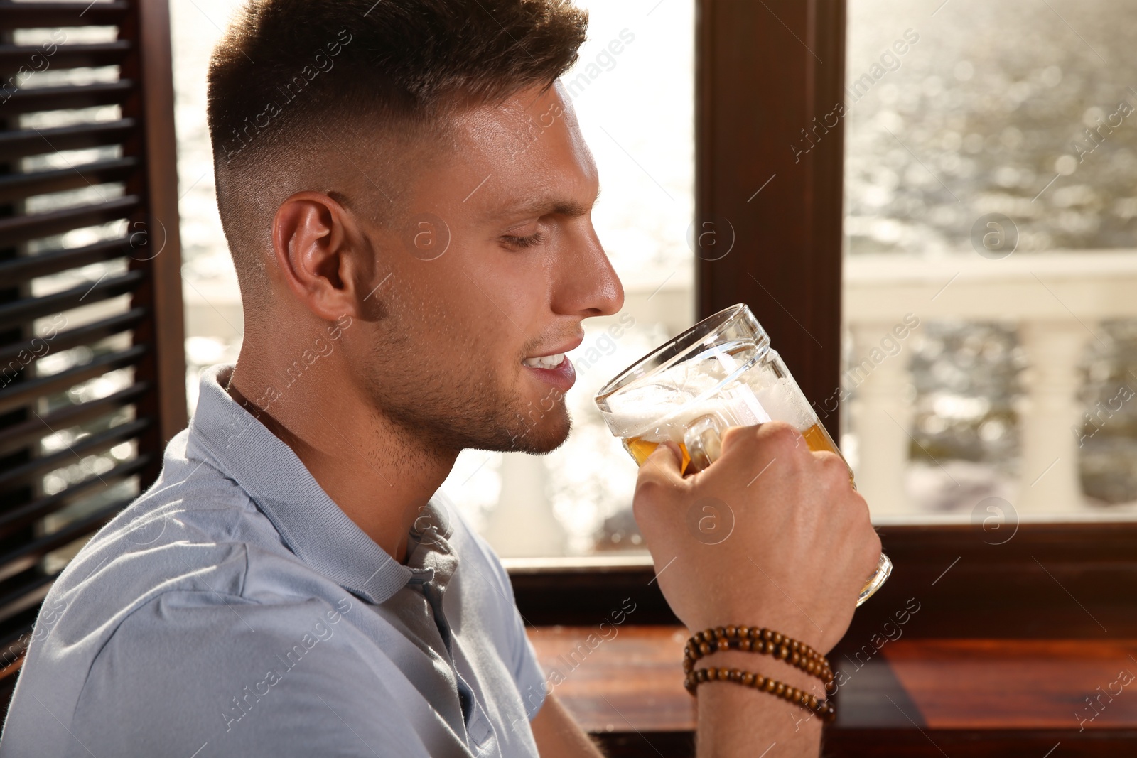 Photo of Young man drinking tasty beer in pub