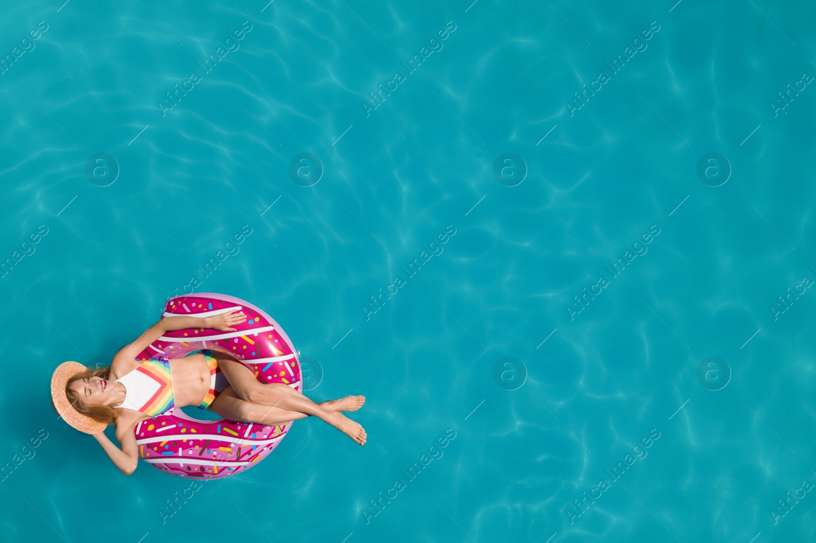 Image of Young happy woman with inflatable ring in swimming pool, top view and space for text. Summer vacation