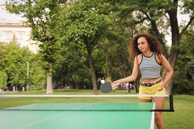 Photo of Young African-American woman playing ping pong outdoors