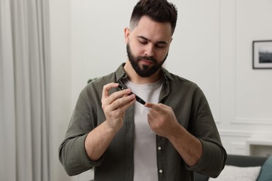 Photo of Diabetes test. Man checking blood sugar level with lancet pen at home