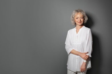 Portrait of mature woman on grey background. Space for text