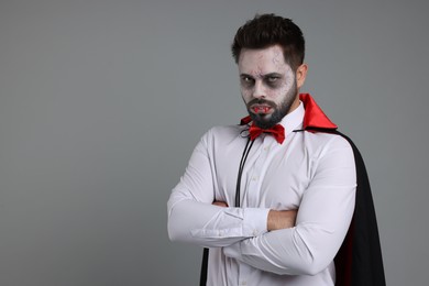 Photo of Man in scary vampire costume with fangs on light grey background, space for text. Halloween celebration