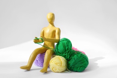 Photo of Human figure made of yellow plasticine knitting with color threads on white background