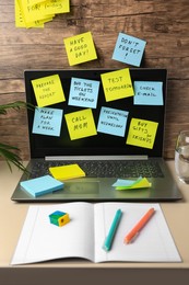 Photo of Many different reminder notes and laptop on table against wooden background