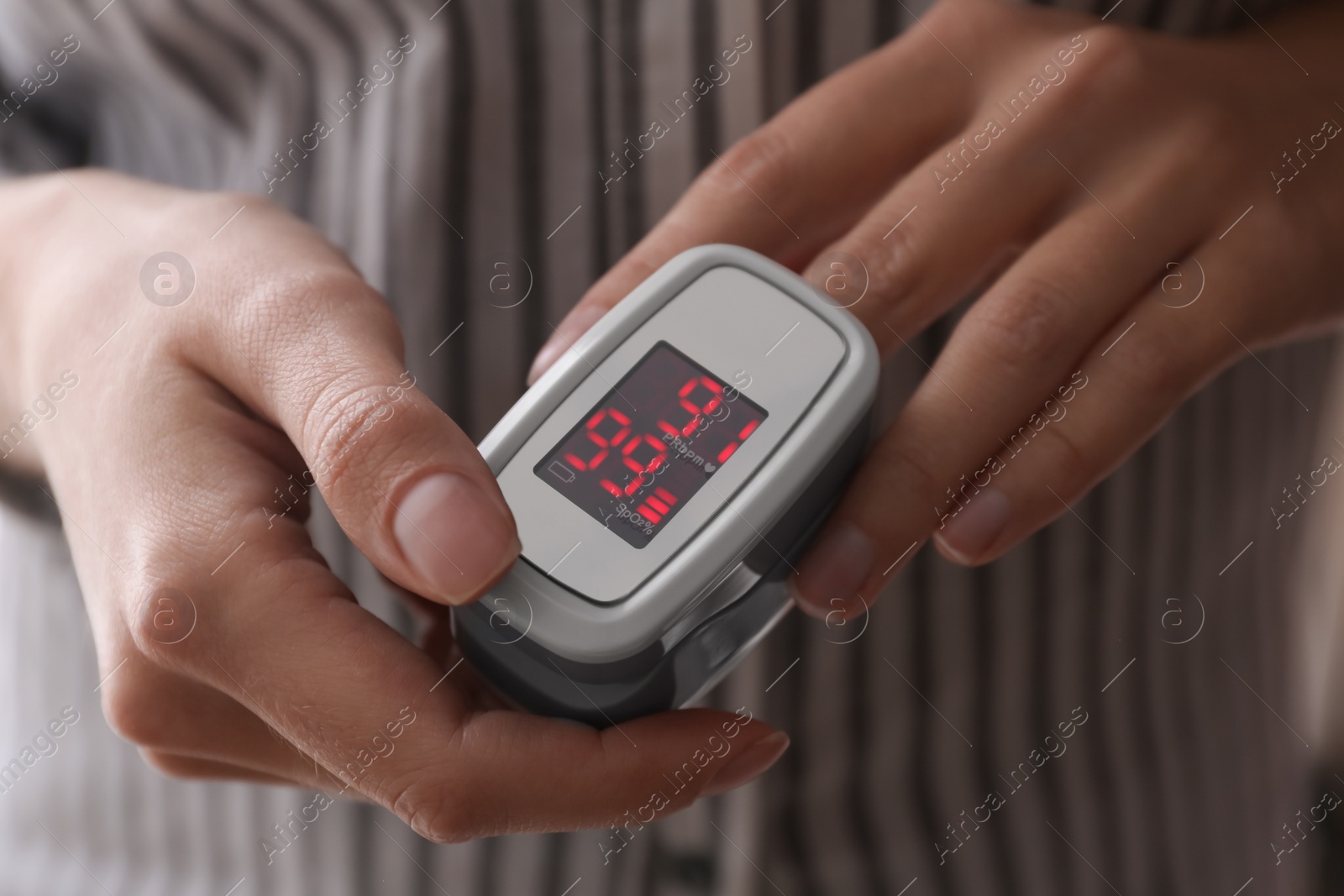 Photo of Woman measuring oxygen level with modern fingertip pulse oximeter, closeup