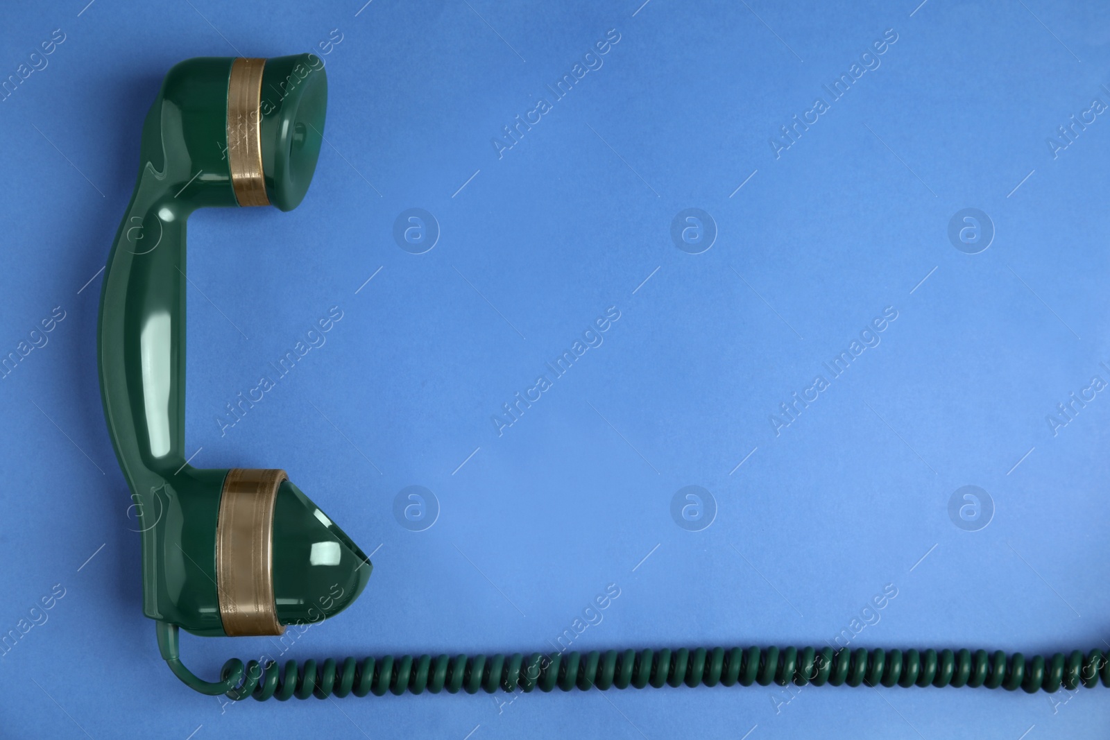 Photo of Handset of vintage green telephone on blue background, top view. Space for text