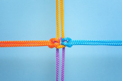 Photo of Different ropes tied together with knot on color background. Unity concept