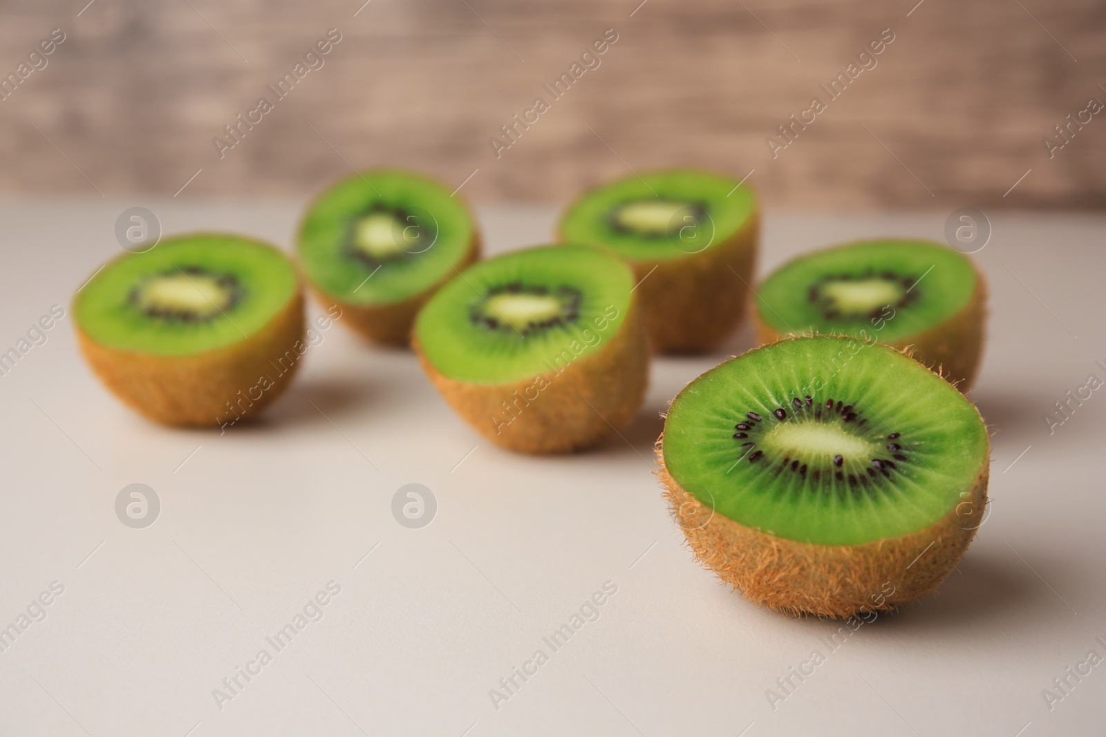 Photo of Halves of fresh kiwis on beige table, closeup. Space for text