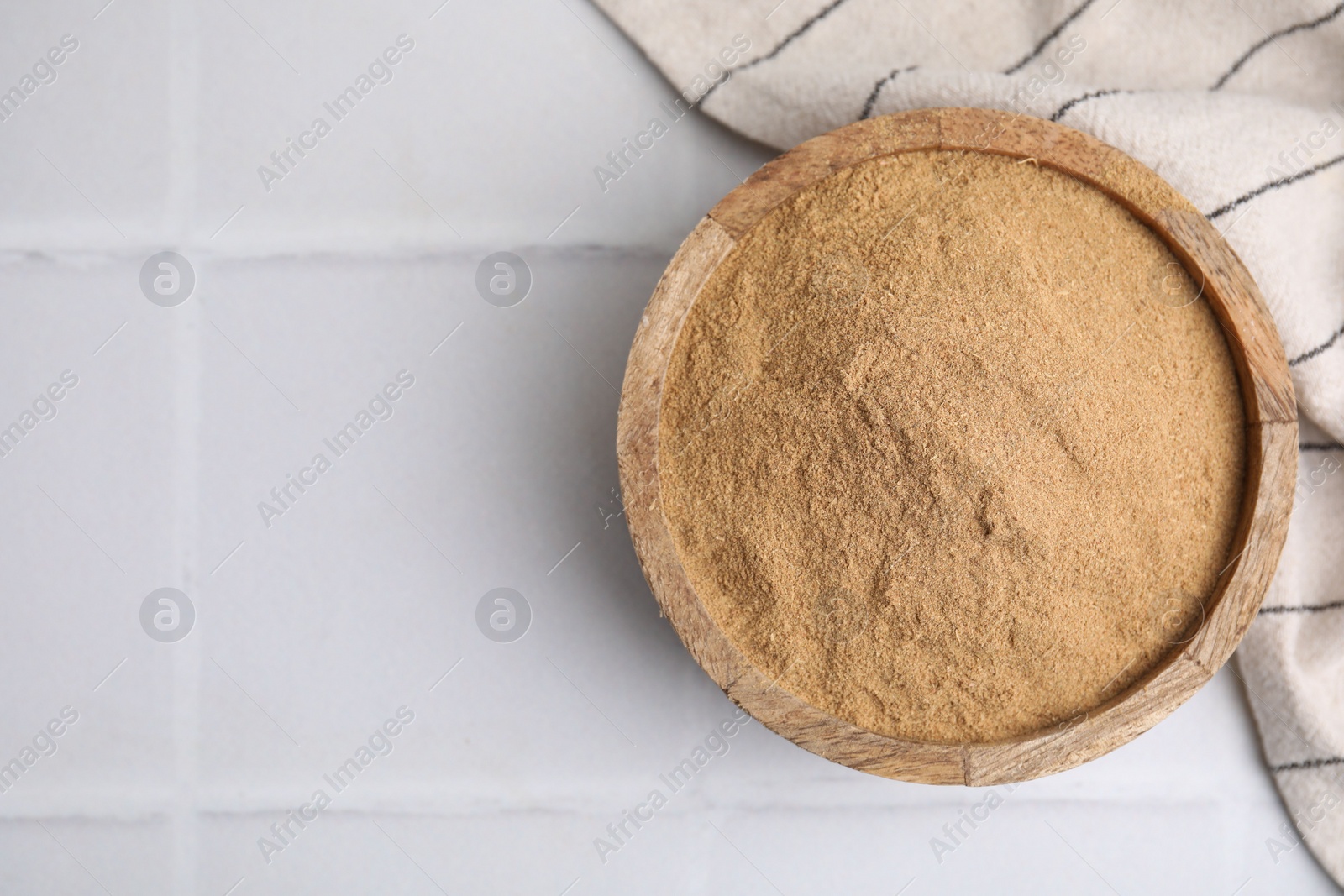 Photo of Dietary fiber. Psyllium husk powder in bowl on white tiled table, top view. Space for text