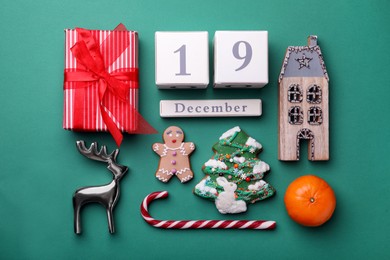 Photo of Saint Nicholas Day layout. Wooden block calendar with date 19th of December, gift box, treats and festive decor on green background
