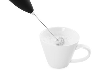 Photo of Whisking milk in cup with mini mixer (frother wand) isolated on white