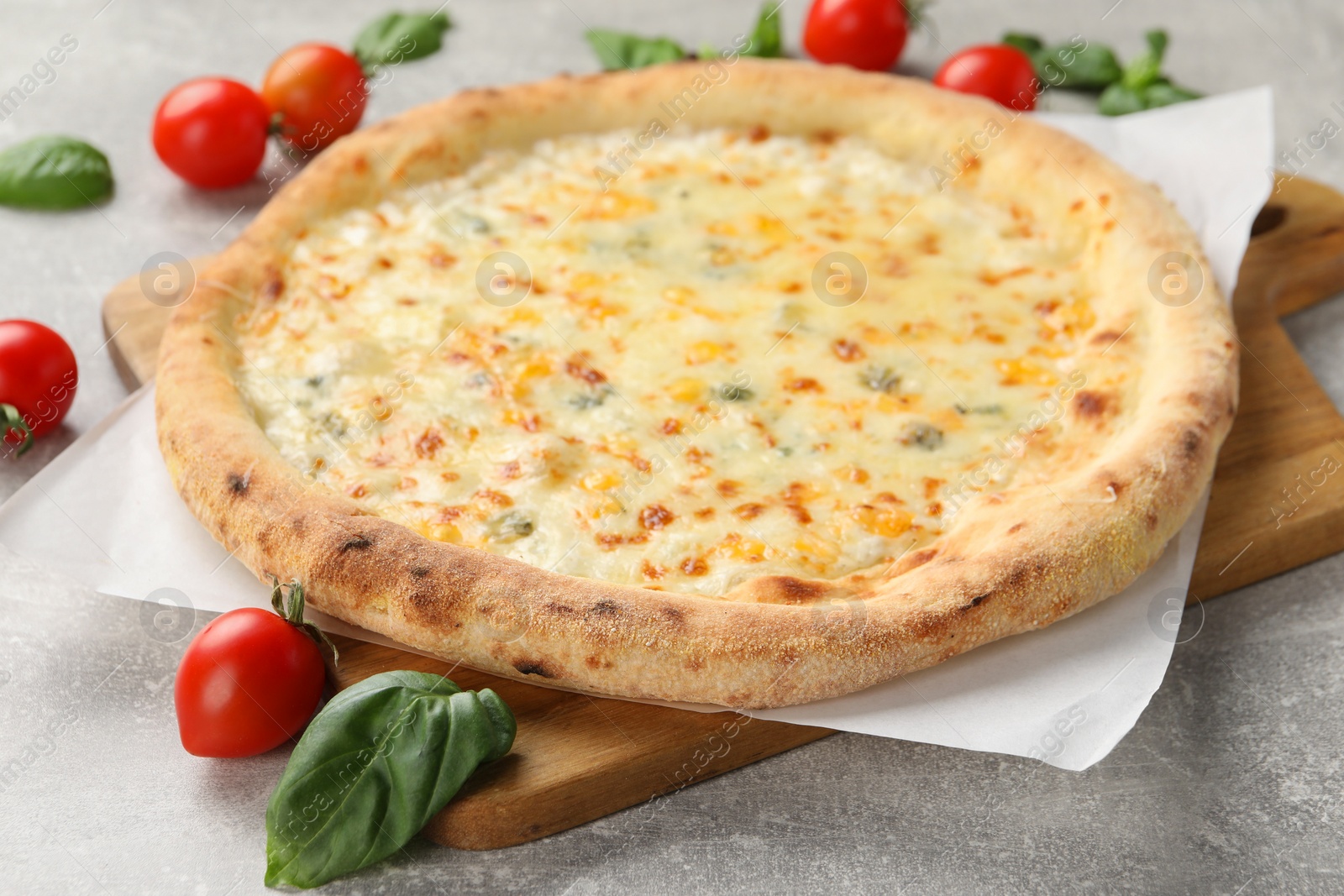 Photo of Delicious cheese pizza, basil and tomatoes on light grey table, closeup