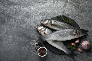 Photo of Tasty sea bass fish on grey textured table, flat lay. Space for text