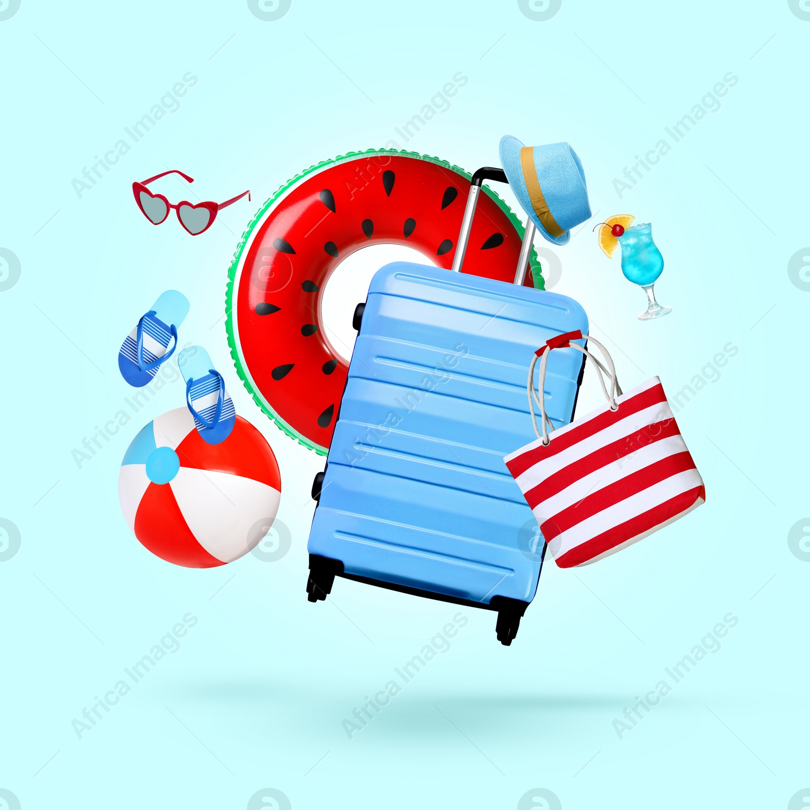 Image of Suitcase, cocktail and beach accessories flying on light blue background