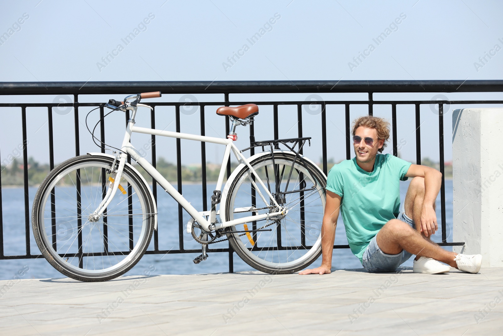 Photo of Handsome young man with bicycle outdoors on sunny day