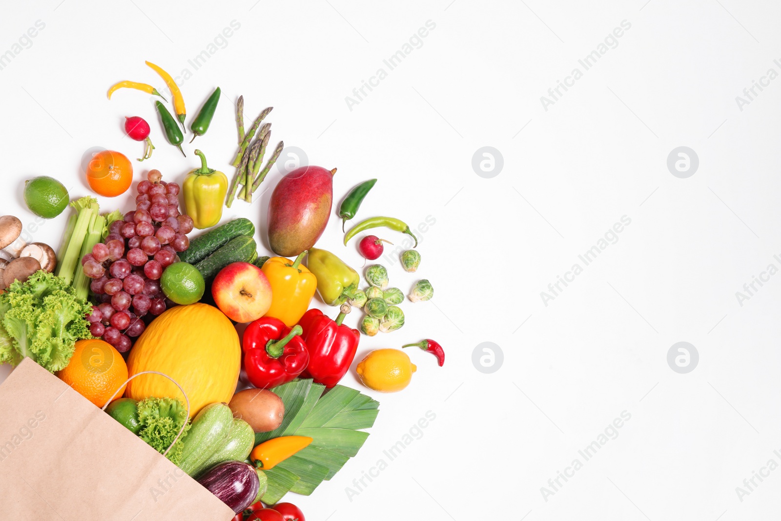 Photo of Paper bag with assortment of fresh organic fruits and vegetables on white background, top view