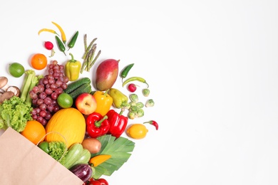 Paper bag with assortment of fresh organic fruits and vegetables on white background, top view