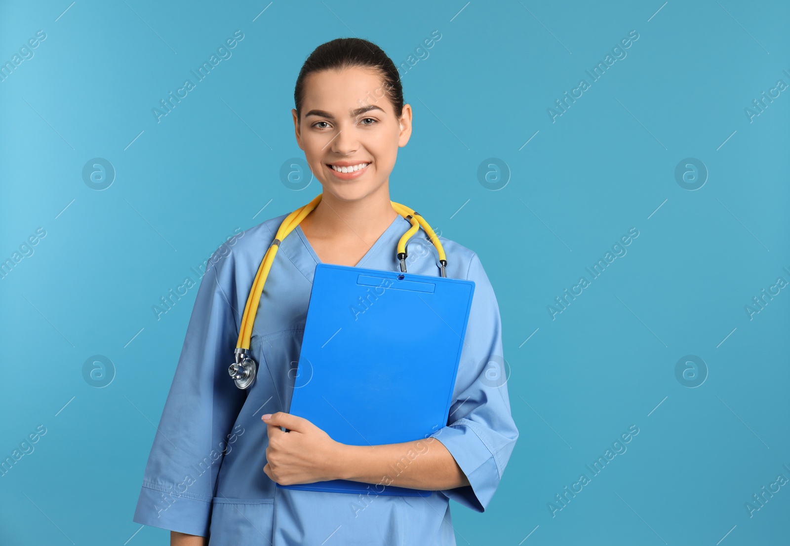 Photo of Portrait of young medical assistant with stethoscope and clipboard on color background. Space for text